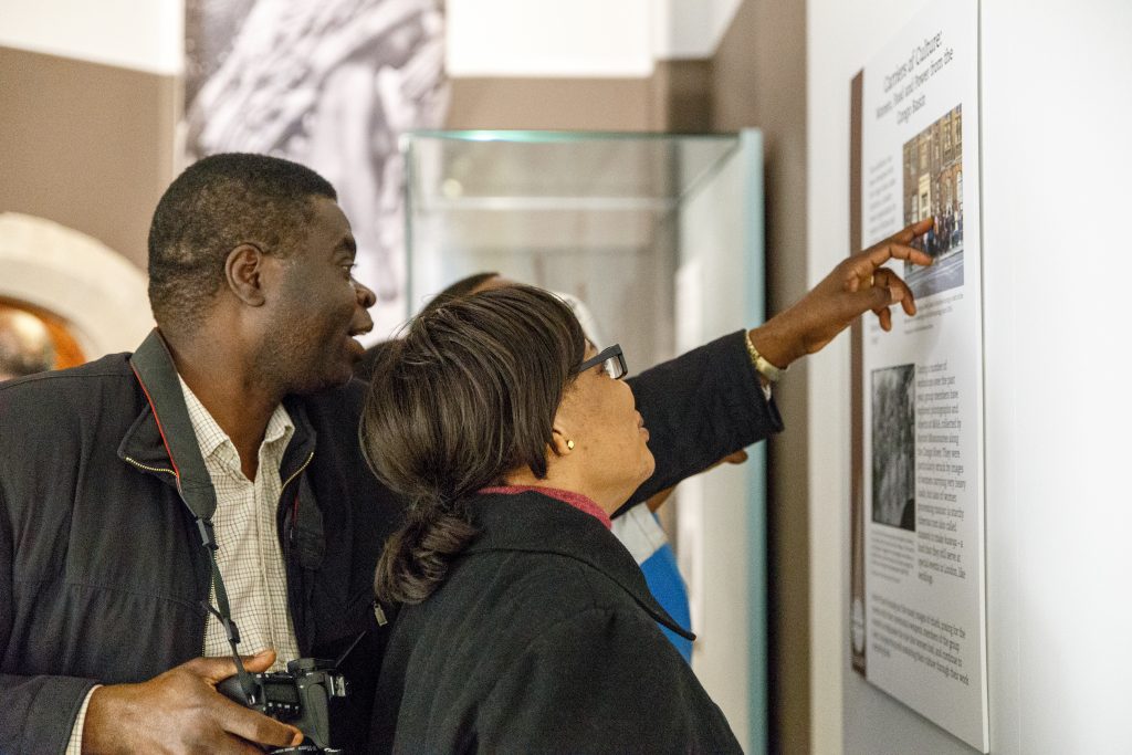 A man and a woman look at some text on a wall of an exhibit