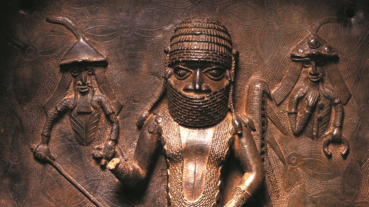 Detail from Benin plaque of Chief Uwangue and Portuguese traders, who are depicted to his left and right. Chief Uwangue is acting as the Oba’s representative to make trade links with the Portuguese, and is holding out the right hand of friendship