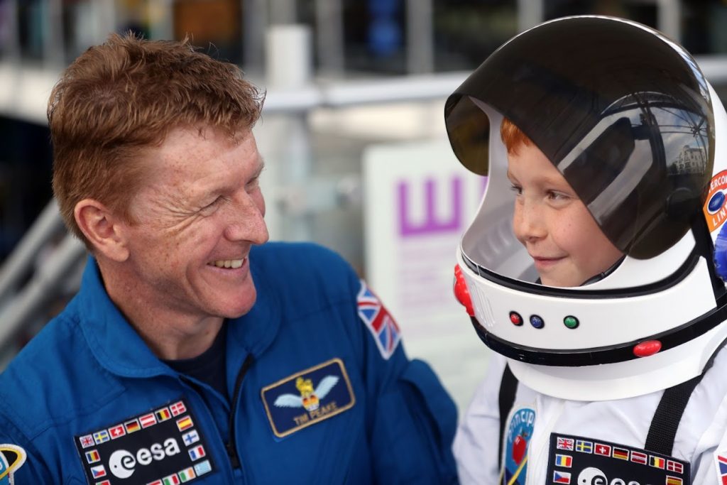 A man talks to a young boy wearing an astronaut costume